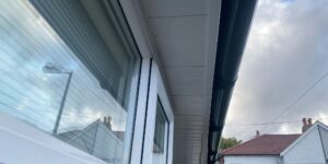 View of the completed roofline with white UPVC fascia and soffit, and black half-round guttering in Chingford.