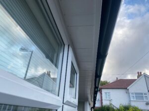 View of the completed roofline with white UPVC fascia and soffit, and black half-round guttering in Chingford.