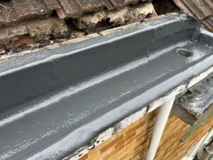 Completed concrete gutter repair with a clean, sealed, and waterproof finish in grey resin.