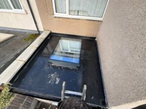 View from above of a completed EPDM flat roof with a central skylight window fitted at the rear of a house in Enfield.