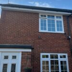 Front of home with clean white uPVC fascia and soffit, black deepflow guttering, and repaired roofline following replacement.