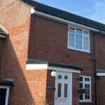 Finished front of red brick house with new white uPVC fascia, soffit, and black guttering installed above the door and window.