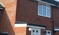 Finished front of red brick house with new white uPVC fascia, soffit, and black guttering installed above the door and window.
