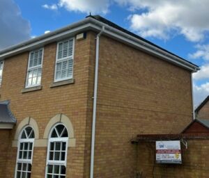 Side of the property showing new white uPVC fascia and guttering with SM Roofline site board