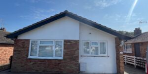 Front view of completed roofline replacement with black fascia, white soffit and black guttering on bungalow property