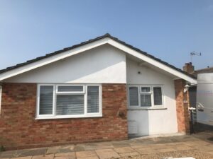 Front view of bungalow before roofline replacement showing original white fascia and guttering